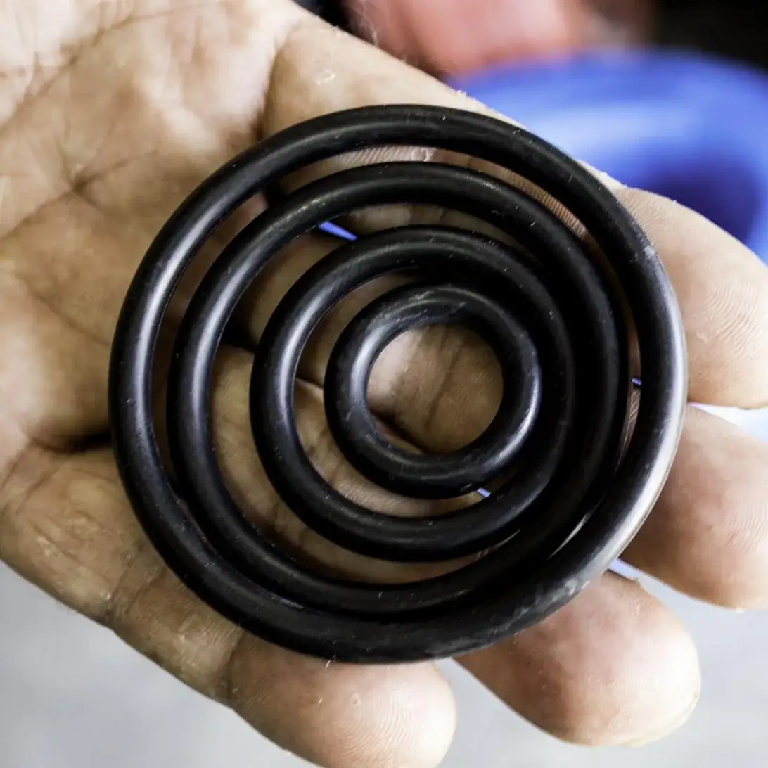 Mano sosteniendo O-rings de goma de distintos diámetros